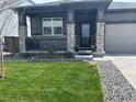 Beautifully landscaped front yard with lush green grass and stone accents on the home's facade at 13432 Broad Wing Dr, Parker, CO 80134