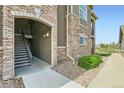 Exterior view of condo featuring brick accents and staircase leading to unit 7 with well maintained landscaping at 2985 Blue Sky Cir # 7-107, Erie, CO 80516