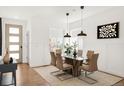 Bright dining area with modern light fixture, glass table, decor, and white wall paneling at 11041 Richfield Cir, Commerce City, CO 80022