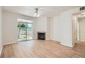 Bright living room featuring a ceiling fan, fireplace, wood floors, and sliding glass door to patio at 8500 E Jefferson # 3C, Denver, CO 80237