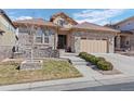 Charming home with a stone facade, tile roof, manicured lawn, and a convenient two-car garage at 10662 Skydance Dr, Highlands Ranch, CO 80126