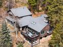 Aerial view of log cabin with multiple outdoor living spaces, mature trees, and stone accents at 39 Pat Creek Rd, Evergreen, CO 80439