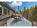 Beautiful deck with dining table, grill, and comfortable seating with views of the surrounding trees at 39 Pat Creek Rd, Evergreen, CO 80439