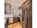 Well-equipped kitchen featuring stainless steel appliances, granite countertops, and wooden floors at 9813 E Carolina Pl, Aurora, CO 80247