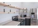 Kitchen with stainless steel appliances, open wood shelving, and neutral countertops and cabinetry at 10035 E Carolina Pl # 201, Aurora, CO 80247