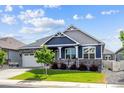 Charming blue two-story home with landscaped yard, stone accents, and a covered porch with rocking chairs at 8888 Falcon St, Longmont, CO 80504