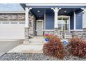 Inviting front porch with stone accents, rocking chairs, and a blue planter at 8888 Falcon St, Longmont, CO 80504