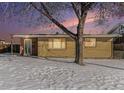 Brick ranch home with snowy yard, illuminated at dusk at 7674 Stuart St, Westminster, CO 80030