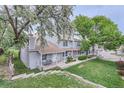 Townhome exterior view showing lawn, front decks, and mature trees at 8136 Washington St # 141, Denver, CO 80229