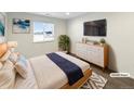 Bright staged bedroom featuring hardwood floors, modern decor, a window, and a TV at 3520 Little Bell Dr, Frederick, CO 80516