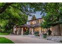 Elegant home showcasing a stone and stucco exterior, complemented by lush greenery and a charming covered entrance at 9678 E Powers Dr, Greenwood Village, CO 80111