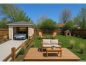 This backyard offers a wooden deck with outdoor seating, lush lawn and a detached garage at 1171 Quebec St, Denver, CO 80220