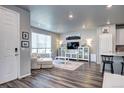 Bright living room with laminate flooring, large windows, and stylish white furniture at 952 Morning Glory Rd, Brighton, CO 80640