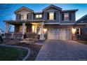 Two-story brick home featuring a covered porch, manicured lawn, and attached two-car garage at 23426 E Ottawa Dr, Aurora, CO 80016