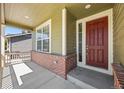 View of the front porch of a charming home, featuring a brick base, a painted door, and a covered entrance at 14912 Vienna Cir, Parker, CO 80134