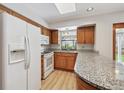 Close-up of kitchen featuring wood cabinets, granite counters, stainless fridge and appliances, and bright natural light at 6247 S Locust St, Centennial, CO 80111