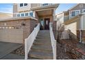 The brick front entrance has a stairway, with a glass detailed door, and small rock landscaping at 4787 Dunkirk St, Denver, CO 80249