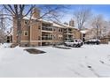 Exterior angle of a brown condo building with balconies and snow-covered parking lot at 10950 W Florida Ave # 303, Lakewood, CO 80232