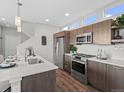 Modern kitchen with stainless steel appliances, quartz countertops, and dark wood cabinets at 1996 W 66Th Ave, Denver, CO 80221