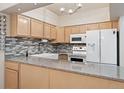 Kitchen with granite countertops, tile backsplash, white appliances, and farmhouse sink at 4195 W 111Th Cir, Westminster, CO 80031