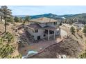 An aerial view of the rear exterior features a balcony, sunroom, brick patio, and lush greenery at 457 Buena Vista Rd, Golden, CO 80401