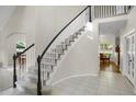 Elegant foyer with a curved staircase, white tile flooring, and abundant natural light at 7420 S Houstoun Waring Cir, Littleton, CO 80120