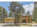 Two-story log home with a two-car garage and a curved driveway at 7350 Fremont Pl, Larkspur, CO 80118