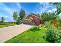 Beautiful home featuring a lush green lawn, mature trees, and a long driveway leading to a spacious three-car garage at 16500 Hitching Post Cir, Parker, CO 80134