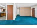 Open-concept living room featuring blue carpeting, light walls, and views into the kitchen at 2842 S Newport St, Denver, CO 80224