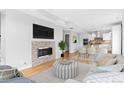 Open-concept living room with fireplace, hardwood floors, and seamless flow to the kitchen and dining area at 1284 Tennyson St # 1, Denver, CO 80204