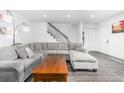 Bright living room featuring a large sectional sofa, wood floors and modern staircase at 4663 S Lowell Blvd, Denver, CO 80236
