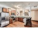 Well-lit kitchen with stainless steel appliances, wood cabinets, and bar seating at 1210 E Colfax Ave # 206, Denver, CO 80218