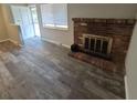 Open living room featuring a brick fireplace and modern wood-look flooring at 12063 E Arizona Dr, Aurora, CO 80012