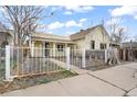 Charming yellow home with white trim and a decorative wrought iron fence at 4764 High St, Denver, CO 80216