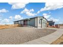 New home exterior with gray siding, brick accents, red door and a gravel yard ready for landscaping at 9274 Biscay St, Commerce City, CO 80022