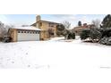 Lovely two-story house features an attached garage, a big drive way, and snow-covered lawn at 3860 Dudley St, Wheat Ridge, CO 80033