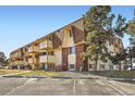 Three-story apartment building featuring brick accents, individual balconies, and reserved parking spaces at 10211 Ura Ln # 304, Thornton, CO 80260