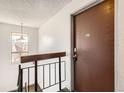 Hallway view featuring a stairwell, hanging lamp, and the front door to an apartment numbered 304 at 10211 Ura Ln # 304, Thornton, CO 80260