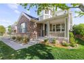 Inviting covered front porch featuring brick accents, a welcome sign, and a well-maintained lawn at 6040 Virgil St, Arvada, CO 80403