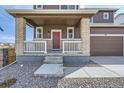 Inviting front porch with brick pillars, white railings, and concrete steps leading to the front door at 798 Sawdust Dr, Brighton, CO 80601