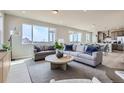 Bright living room featuring large windows, comfortable sofas, a round coffee table, and an open floor plan at 798 Sawdust Dr, Brighton, CO 80601