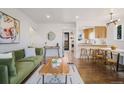 A stylish living space with hardwood floors, a cozy green sofa, and an open layout leading to the kitchen at 3379 Krameria St, Denver, CO 80207