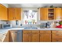 Well-lit kitchen with oak cabinets, stainless steel dishwasher, and window with plants at 5106 Eagle Ct, Denver, CO 80239