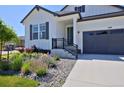 Inviting front exterior featuring manicured landscaping and a welcoming entrance with charcoal gray garage doors at 1160 Spencer Pl, Erie, CO 80026