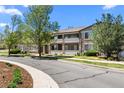 Well-maintained exterior view of a condominium with stone accents, mature trees, and street frontage at 9397 Las Ramblas Ct # D, Parker, CO 80134