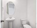 Clean powder room featuring a pedestal sink and modern toilet at 45910 Gentry Ave, Bennett, CO 80102