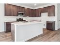 Modern kitchen with stainless steel appliances, dark cabinets, and a white center island at 45910 Gentry Ave, Bennett, CO 80102