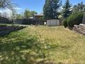 A large grassy backyard featuring a storage shed and split rail fence at 3961 S Uravan St, Aurora, CO 80013