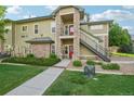 Two-story condo featuring stone accents, a walkway, green lawn and small bushes at 5800 Tower Rd # 1201, Denver, CO 80249