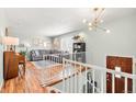 Bright living room featuring hardwood floors, a stylish light fixture, a cozy gray sectional, and a front entry staircase at 15876 E Flora Pl, Aurora, CO 80013